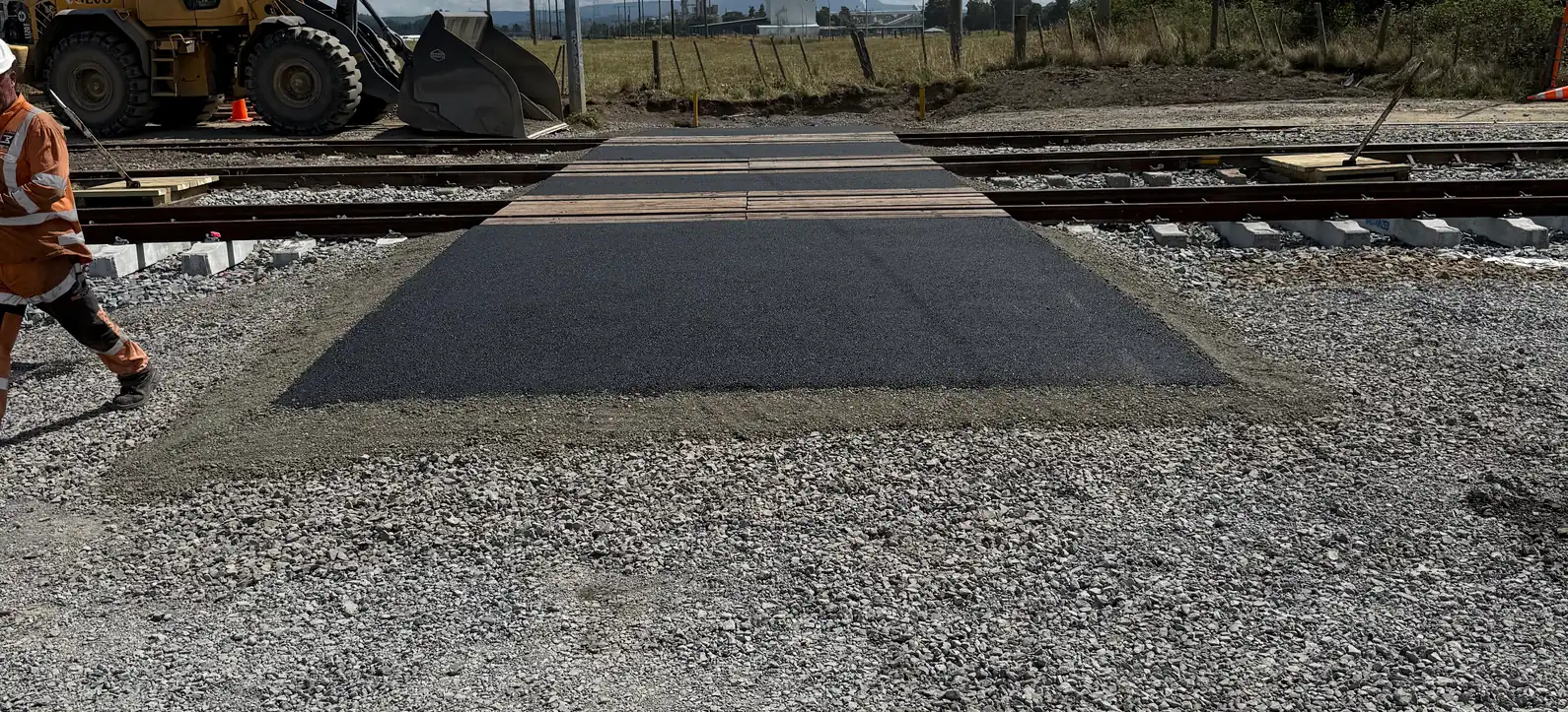 Loader placing hardfill over a geotextile mat on a sandy site beneath the power lines