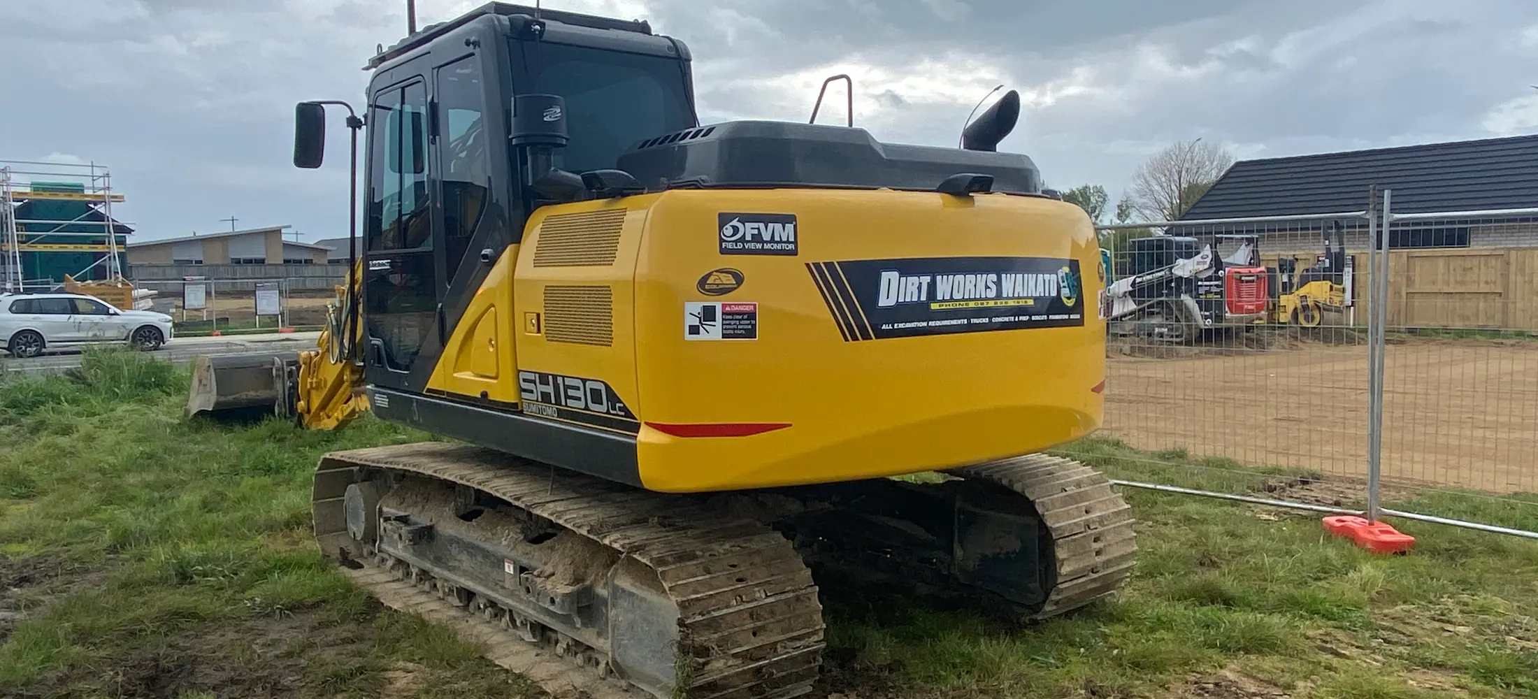 The branded Dirt Works Waikato excavator standing on a fenced residential site