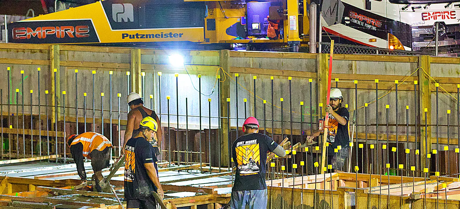 Night concrete pour on a commercial job, the crew working the deck with a boom pump overhead
