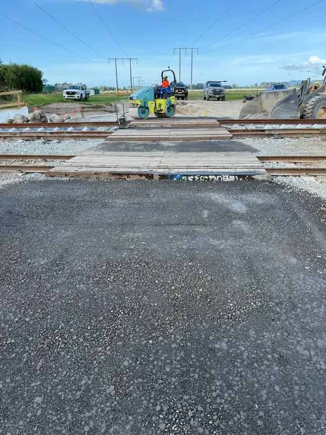 Compacted basecourse laid up to a rail crossing with a roller working in the background