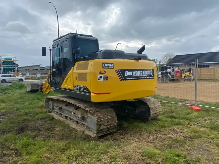 The branded Dirt Works Waikato excavator standing on a fenced residential site