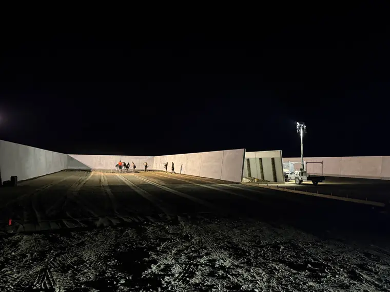 Crew and lighting tower at a silage bunker pour running on into the night