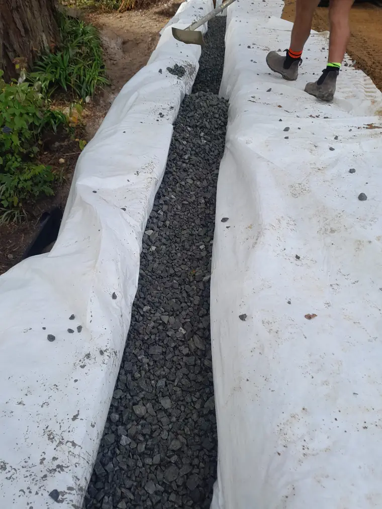 Completed geotextile-wrapped subsoil drain backfilled with drainage metal, ready to be closed up