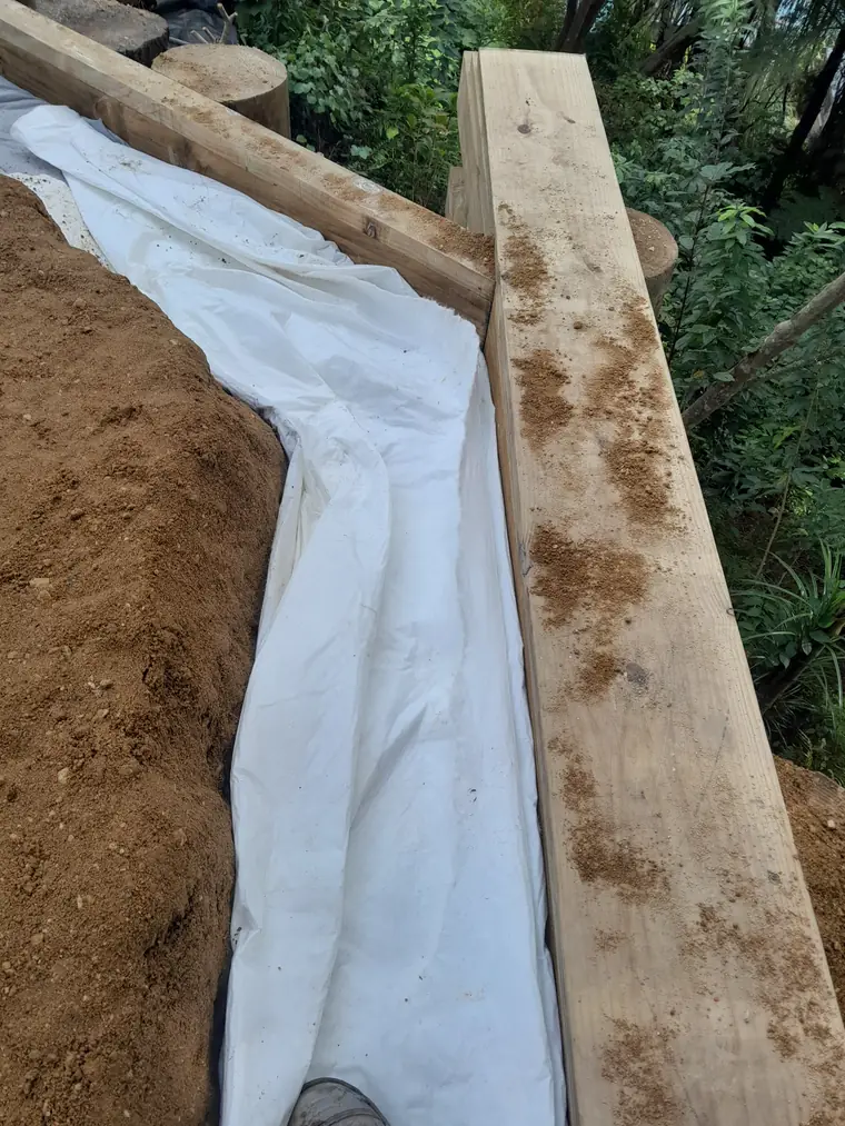 Geotextile laid into an open trench with the drainage coil in place before backfilling