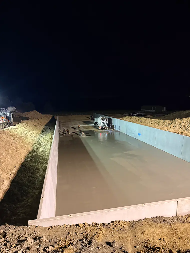 Newly poured feed pad floor between its concrete walls, lit for the night shift